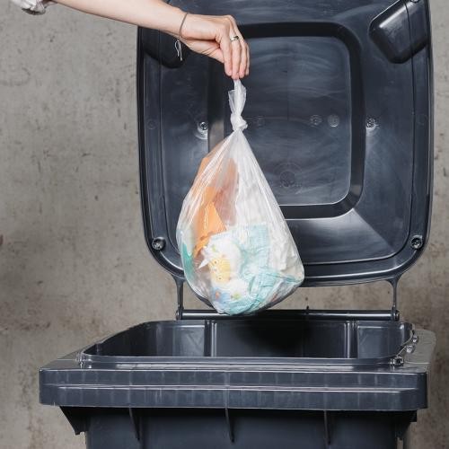 Restmülltonne Restmülltonne mit offenem Deckel, in die eine Mülltüte eingeworfen wird.