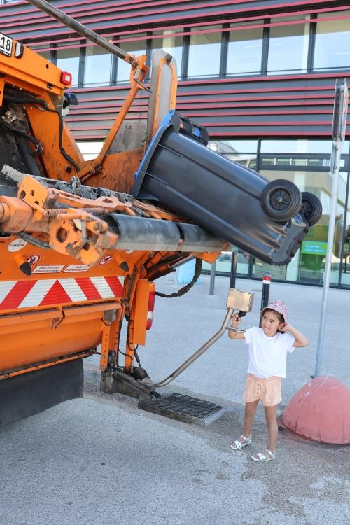 Ein Kind leert eine Mülltonne