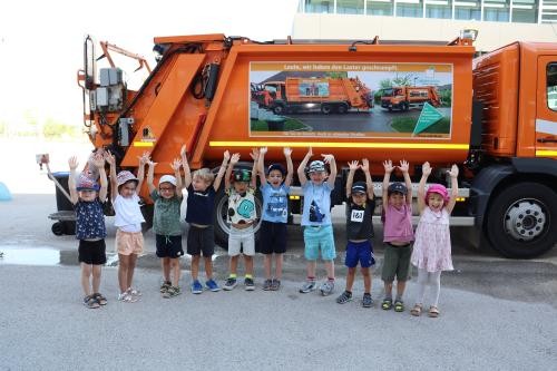Müllabfuhr mit strahlenden Kindern davor