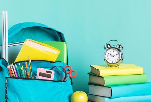 Schulmaterialien Schulranzen, Bücher und ein Wecker
